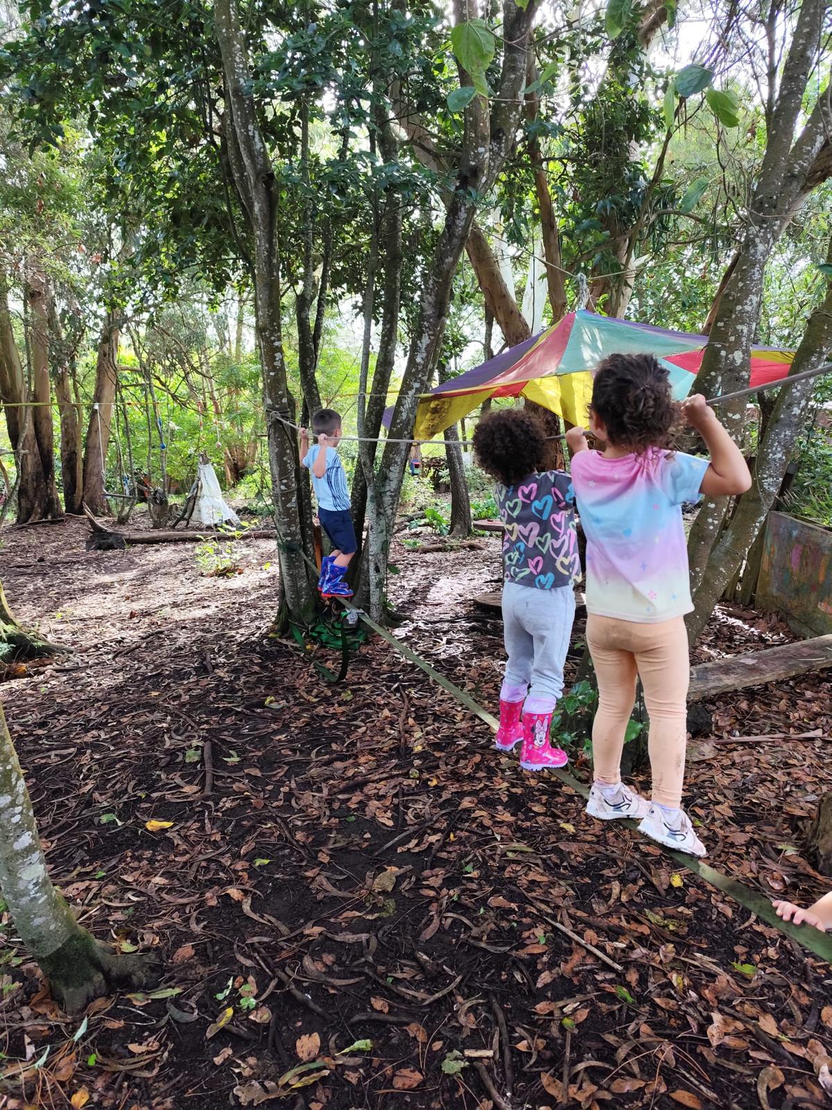 Crianças a equilibrar-se numa slackline na mata