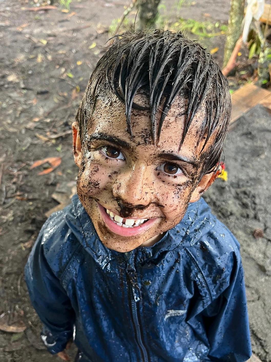Criança sorridente com cara cheia de lama na Mata do Pópulo